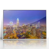 Art deco poster of Charlotte skyline in muted gray and blue tones, acrylic print framed in white.