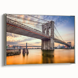 Framed canvas of the Brooklyn Bridge in grayscale with colorful skyline backdrop, ideal for modern living room decor.