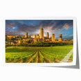 Rolled print of Tuscany landscape with lush green fields and distant hills, in soft earth tones.
