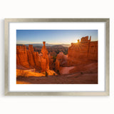 Textured art print of Bryce Canyon in muted orange and red tones on a framed silver mat, suitable for bedroom decor.