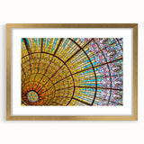 Abstract art print of Barcelona skyline in muted gold and blue tones, framed with a golden mat.