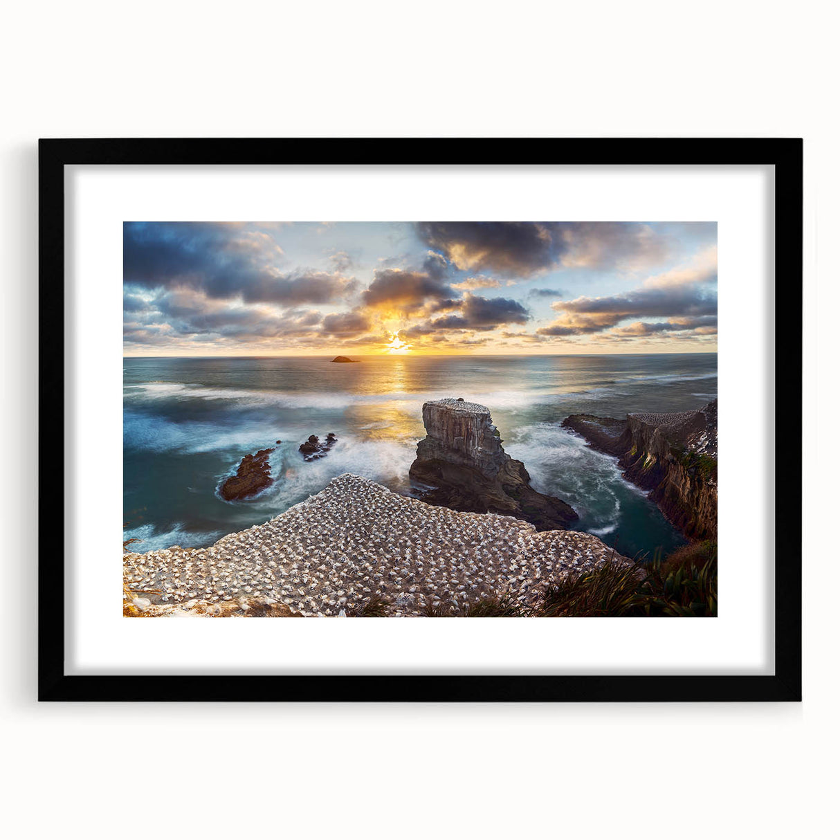 Abstract art print of New Zealand's west coast in vibrant colors on a large textured canvas, framed in black.