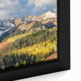 Close-up of a textured black wall art featuring a vibrant depiction of the Rocky Mountains on a framed canvas.