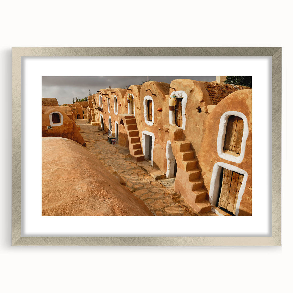 Textured art print of an abstract Tunisian landscape in earthy tones, framed in silver, ideal for bedroom art.