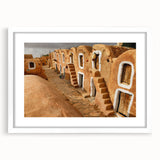 Abstract art print depicting a Tunisian landscape in earthy tones on a framed white mat, suitable for dining room decor.