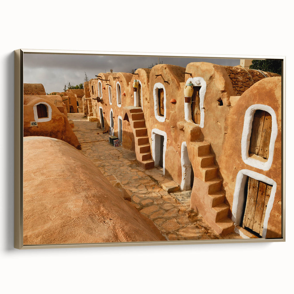 Framed canvas featuring a vintage-style landscape painting of a Tunisian scene in gold and black tones.