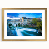 Abstract art print of the Bath, England skyline in muted gold and blue tones on a framed mat.