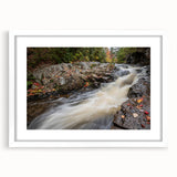 Abstract art print of Acadia's rugged coastline in muted blue and gray tones on a framed white mat.