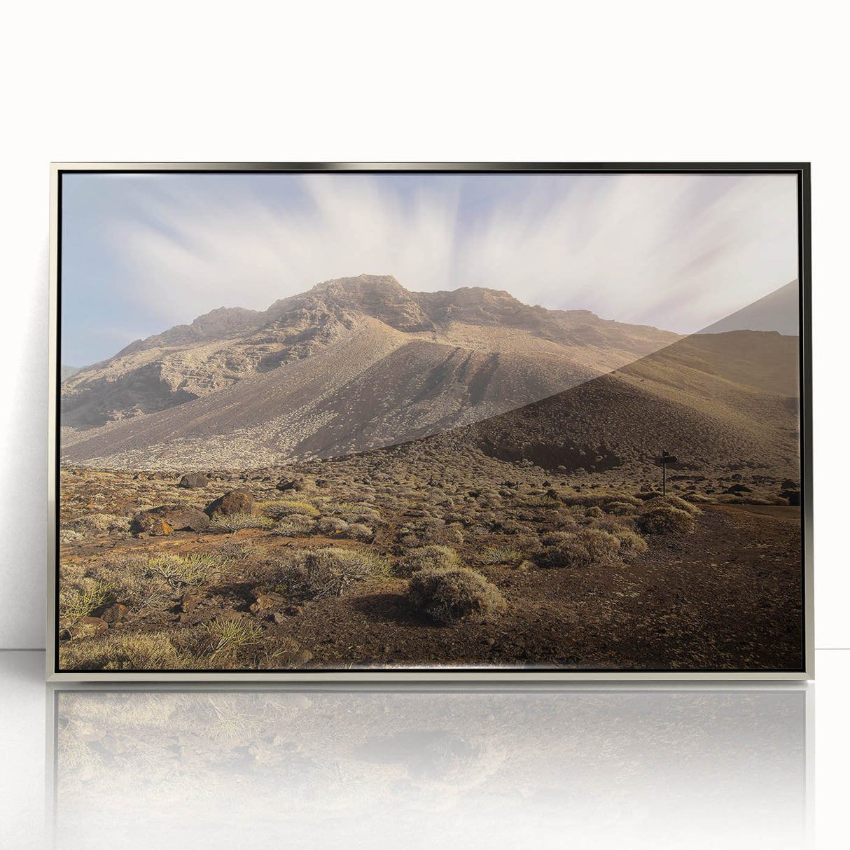 Large art print of a serene European landscape, featuring muted earth tones on a silver-framed acrylic.