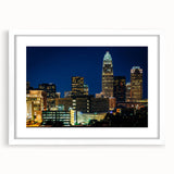 Abstract art print of Charlotte skyline in muted blue tones on a framed white mat, ideal for dining room decor.