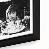 Close-up of black wall art featuring colorful, textured depictions of food and people on a framed canvas.