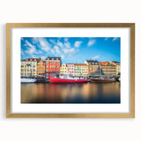 Abstract art print of a European scenery in muted gold and blue tones, framed with a gold mat.