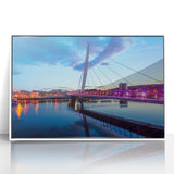 Art deco poster of a Welsh landscape in muted green and blue tones, acrylic print framed in white.