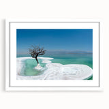 Abstract art print of the Dead Sea in muted blue and beige tones on a framed white mat, suitable for dining room decor.