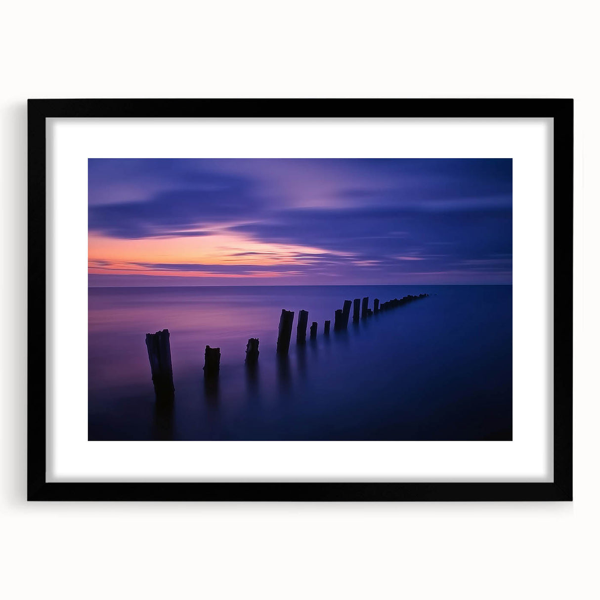 Black-framed landscape artwork featuring a serene beach scene with gentle waves and a clear sky, perfect for home decor and adding a coastal touch to interiors.