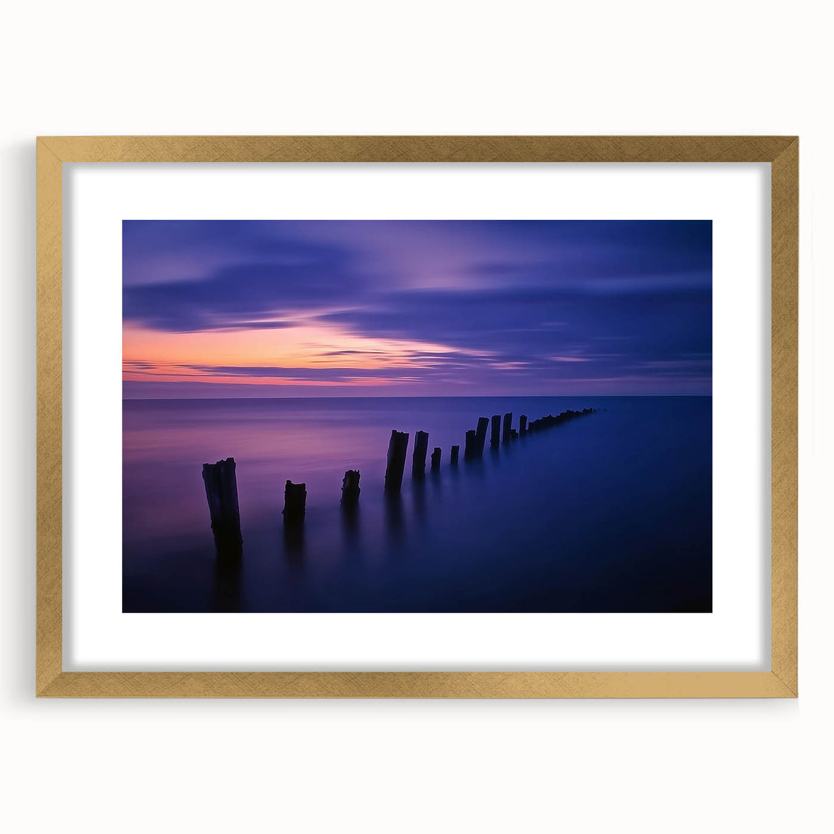 Elegant gold-framed landscape artwork showcasing serene beach scenery with soft waves and sandy shores, complete with a sophisticated mat for added depth. Ideal for home decor and coastal-themed interiors.