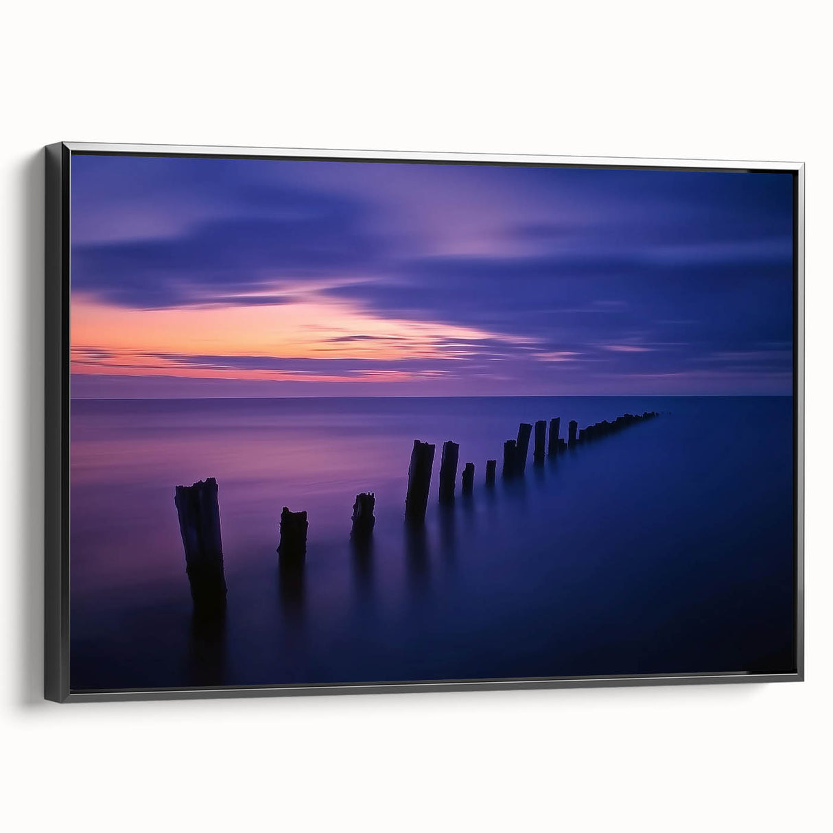 Framed canvas artwork depicting a serene beach landscape, featuring vibrant blues and sandy tones, presented in a sleek black frame, ideal for coastal decor.