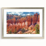 Framed landscape artwork showcasing stunning canyons in vibrant colors, complemented by a silver mat. Ideal for home decor, adding a touch of nature-inspired elegance.