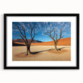 Black-framed landscape artwork depicting a serene desert scene, featuring warm hues of orange and yellow with a textured mat, ideal for home decor enthusiasts.