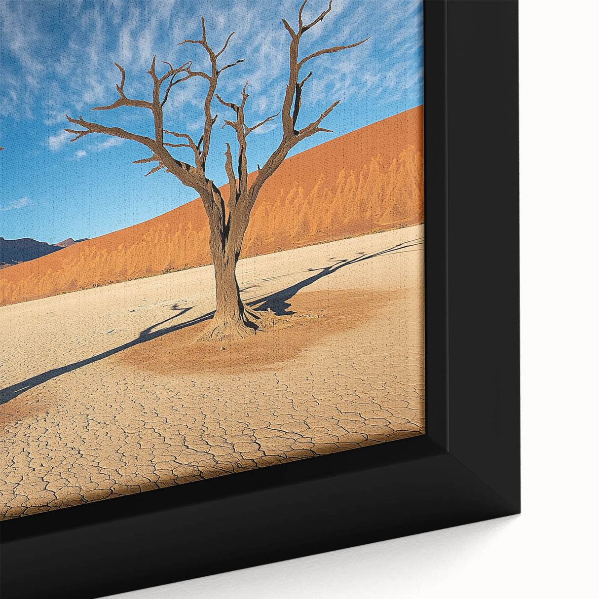 Close-up of a framed desert landscape canvas print, showcasing vibrant sand dunes and a clear blue sky, perfect for adding a serene touch to home decor.