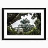 Black-framed landscape artwork showcasing a majestic castle surrounded by lush greenery, elegantly matted for a refined presentation, perfect for home decor.