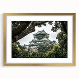 Framed landscape artwork depicting a picturesque castle surrounded by lush greenery, elegantly presented with a gold mat. Ideal decor for elegant interiors.
