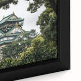 Close-up of a framed canvas depicting a serene landscape featuring a majestic castle surrounded by lush greenery and a vibrant sky, perfect for home decor.