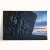 Stretched canvas artwork depicting a dramatic landscape with towering cliffs and vibrant colors, elegantly leaning against a wall, perfect for home decor.
