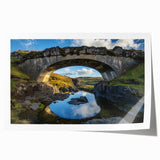 Landscape print of a serene bridge over a river, showcasing vibrant colors and intricate details. Ideal for home decor, the artwork is rolled for easy shipping and display.