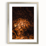 Textured art depicting abstract autumnal leaves in warm orange and brown tones, framed in silver, ideal for bedroom decor.