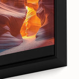 Close-up of a framed canvas print depicting a vibrant desert landscape, showcasing warm hues of orange and yellow, with intricate details of sand dunes and cactus plants, perfect for home decor.
