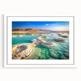 Abstract art print of the Dead Sea in muted blue and beige tones, framed with a white mat, ideal for dining room decor.