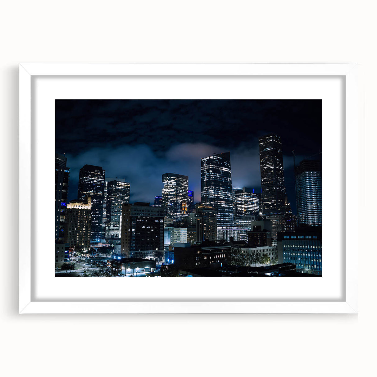Abstract art prints of Houston skyline in muted gray and blue tones on a framed white mat, suitable for dining room decor.