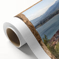 Rolled canvas artwork showcasing a vibrant landscape featuring a majestic castle surrounded by lush greenery and mountains, elegantly packaged in a protective cardboard tube.