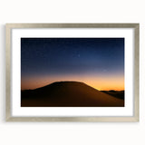 Desert landscape artwork framed in silver with a white mat, showcasing vibrant hues of orange and blue, ideal for modern home decor or office spaces.