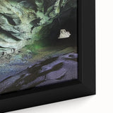 Close-up of a framed canvas print depicting a vibrant landscape with intricate cave designs, showcasing rich colors and textures ideal for home decor.