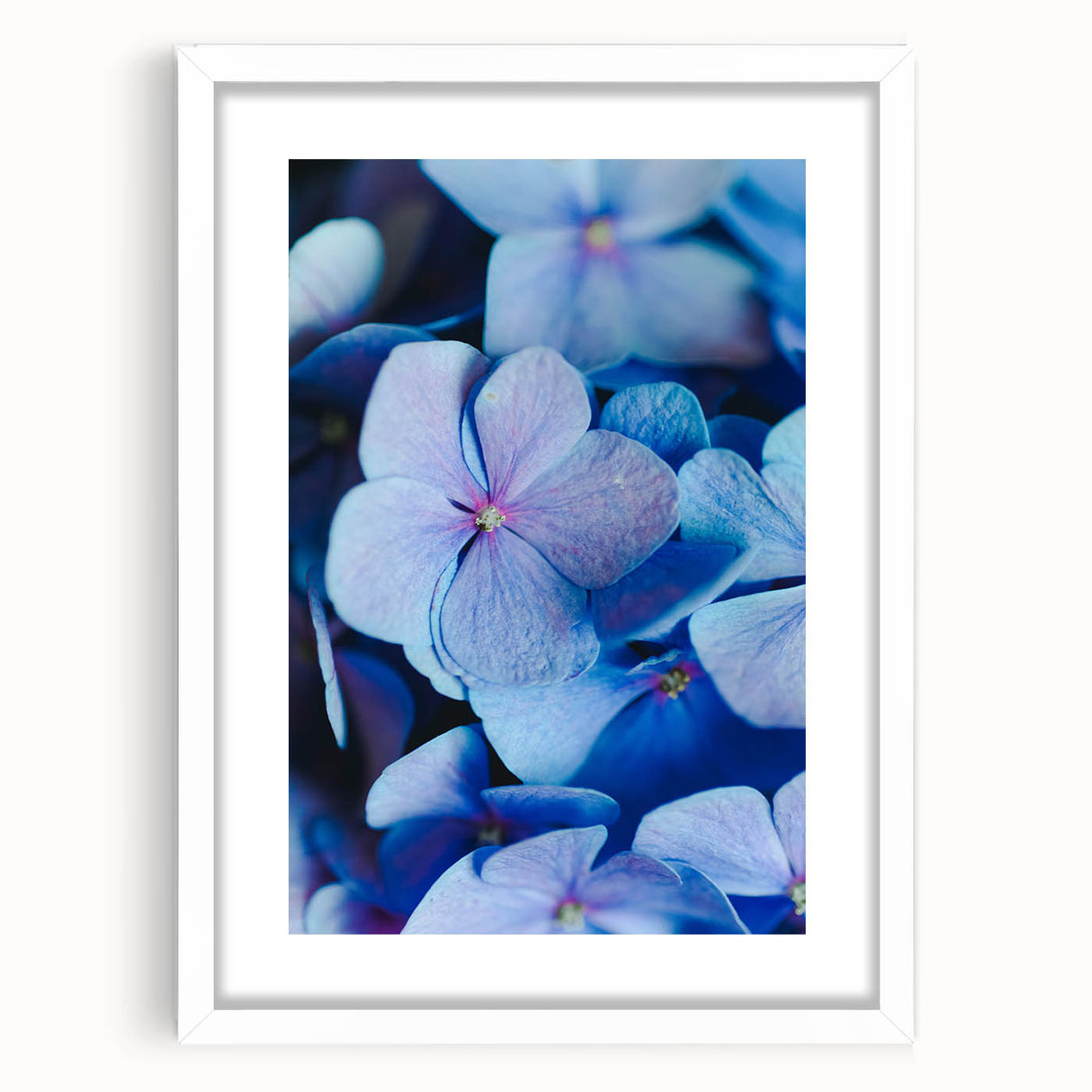 Abstract art print featuring swirls of pink and green, framed in white, suitable for bedroom or dining room decor.