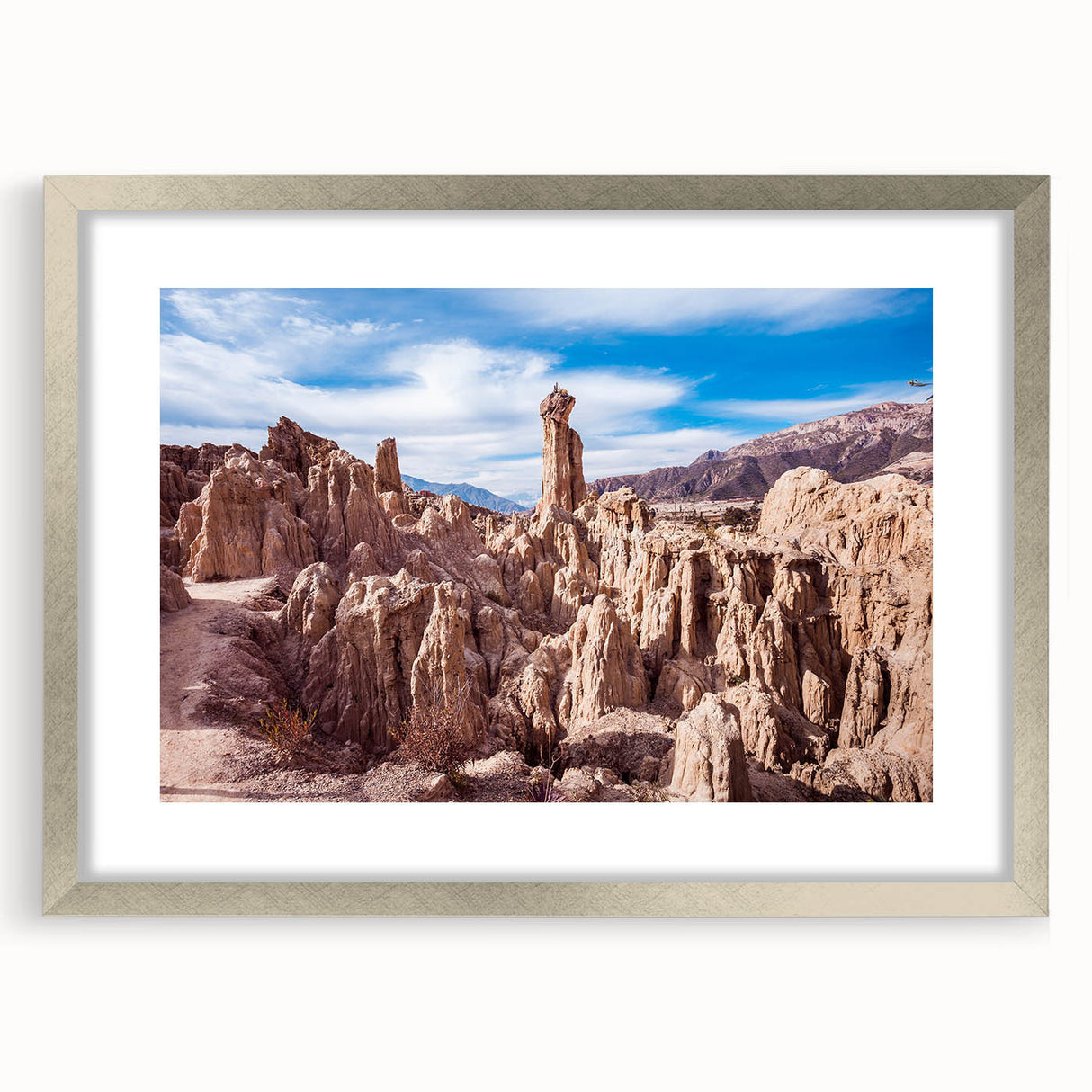 Textured abstract art print of a Bolivian landscape in muted earth tones, framed in silver, suitable for bedroom decor.