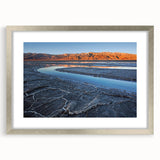 Textured art depicting Death Valley in muted earth tones on a framed silver mat, suitable for bedroom decor.