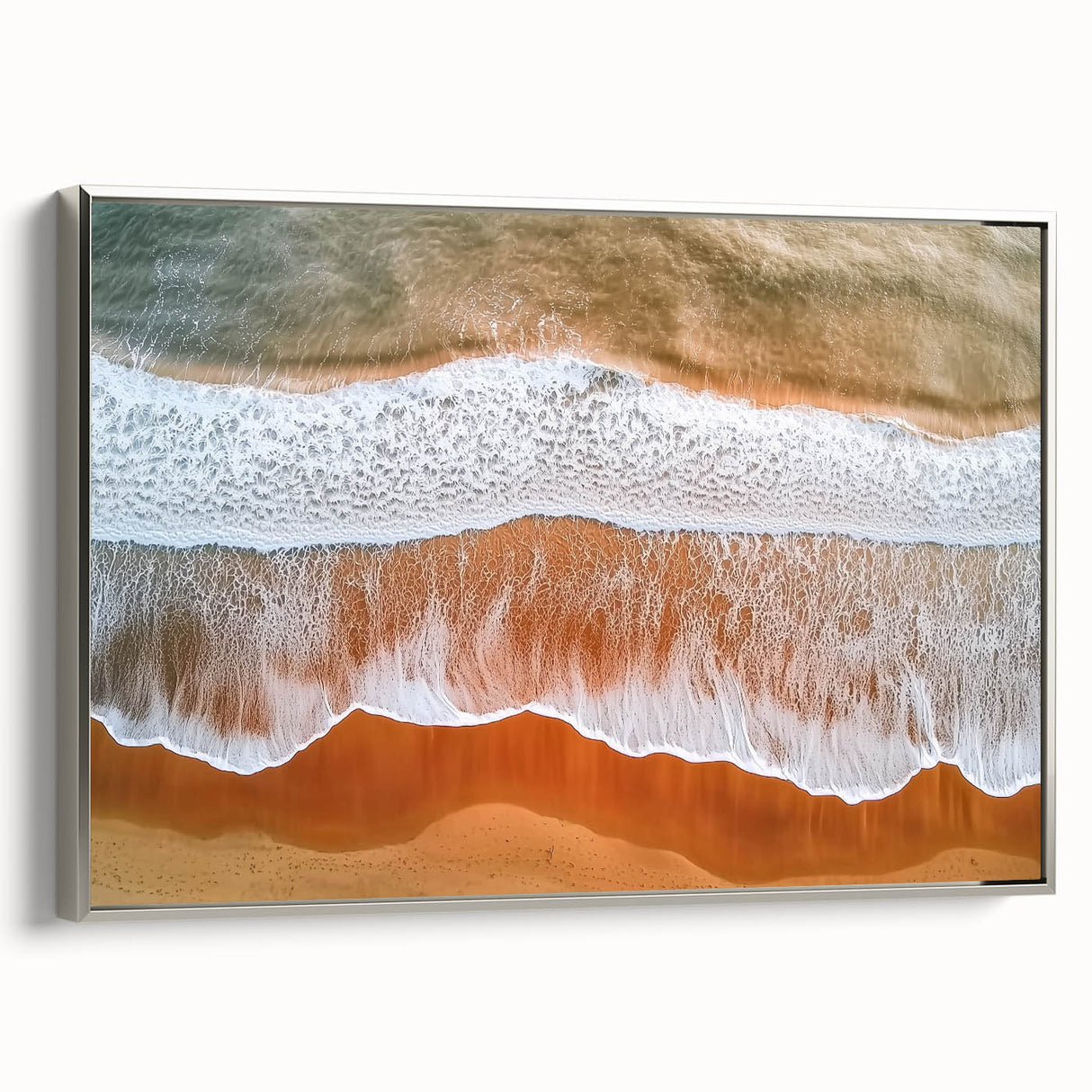 Framed canvas artwork depicting a tranquil beach scene with soft waves and golden sand, featuring a sleek silver frame, ideal for coastal home decor.