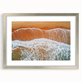 Framed landscape artwork showcasing a serene beach scene with gentle waves and a vibrant sunset, encased in a sleek silver frame with a white mat, perfect for coastal decor.