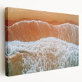 Stretched canvas artwork depicting a serene beach landscape with soft waves and a vibrant sunset, showcasing warm hues of orange and blue, ideal for coastal home decor.