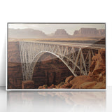 Framed acrylic print of a serene landscape featuring a bridge over a tranquil river, surrounded by lush greenery and soft blue skies, ideal for home decor.