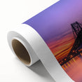 Rolled canvas showcasing a vibrant landscape bridge design, featuring rich colors and intricate details, securely packaged in a protective cardboard tube for shipping.