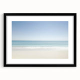 Black-framed landscape artwork featuring a serene beach scene with gentle waves and a clear blue sky, designed to enhance home decor and create a calming atmosphere.