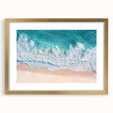 Elegant gold-framed landscape artwork depicting serene beach scene with gentle waves and blue skies, ideal for home decor and coastal-themed interiors.