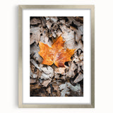 Textured abstract art print in warm orange and red tones, framed in silver, ideal for bedroom wall decor.