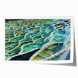 Rolled print of a European scenery featuring a floral foreground and a distant village, in soft pastel colors.