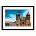Abstract art print depicting a colorful, textured scenery of Oaxaca, in a large black-framed mat.