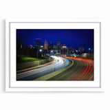Abstract art print of Minneapolis skyline in muted blue and gray tones on a framed white mat, suitable for dining room decor.